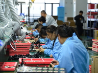 Workers install chips, resistors, and other components on a circuit board in a workshop in Fuyang, Anhui province, China, on November 30, 20...