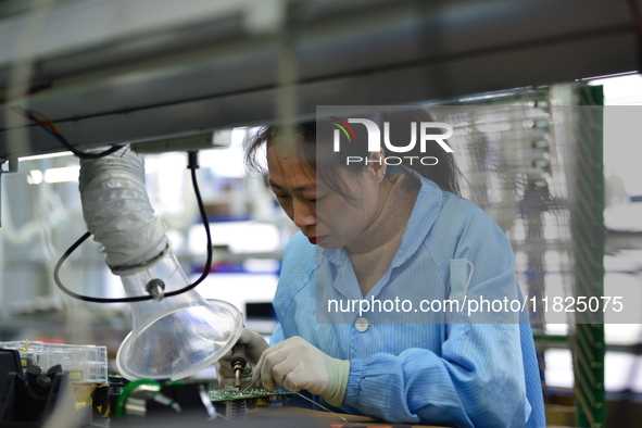 Workers install chips, resistors, and other components on a circuit board in a workshop in Fuyang, Anhui province, China, on November 30, 20...