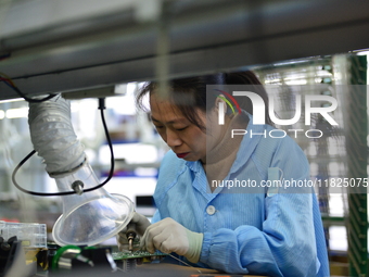 Workers install chips, resistors, and other components on a circuit board in a workshop in Fuyang, Anhui province, China, on November 30, 20...