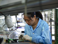 Workers install chips, resistors, and other components on a circuit board in a workshop in Fuyang, Anhui province, China, on November 30, 20...