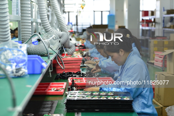 Workers install chips, resistors, and other components on a circuit board in a workshop in Fuyang, Anhui province, China, on November 30, 20...