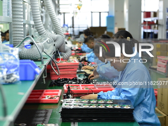 Workers install chips, resistors, and other components on a circuit board in a workshop in Fuyang, Anhui province, China, on November 30, 20...