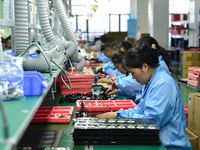 Workers install chips, resistors, and other components on a circuit board in a workshop in Fuyang, Anhui province, China, on November 30, 20...