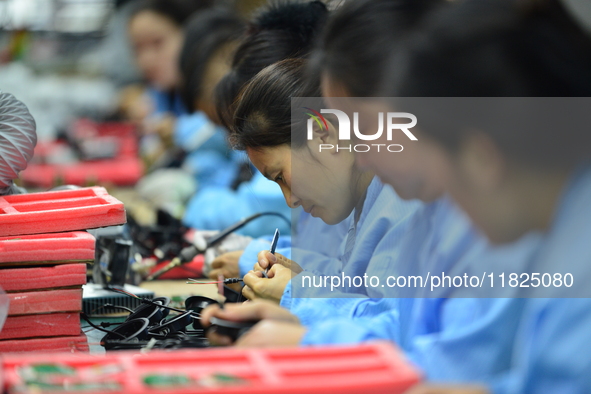 Workers install chips, resistors, and other components on a circuit board in a workshop in Fuyang, Anhui province, China, on November 30, 20...