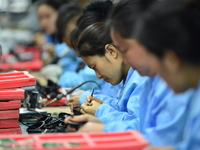 Workers install chips, resistors, and other components on a circuit board in a workshop in Fuyang, Anhui province, China, on November 30, 20...