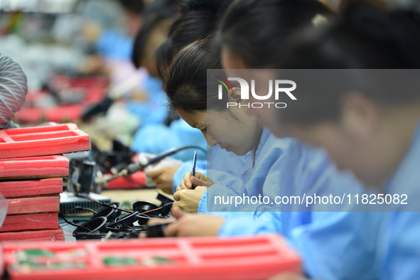 Workers install chips, resistors, and other components on a circuit board in a workshop in Fuyang, Anhui province, China, on November 30, 20...