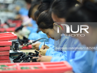 Workers install chips, resistors, and other components on a circuit board in a workshop in Fuyang, Anhui province, China, on November 30, 20...