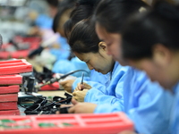 Workers install chips, resistors, and other components on a circuit board in a workshop in Fuyang, Anhui province, China, on November 30, 20...