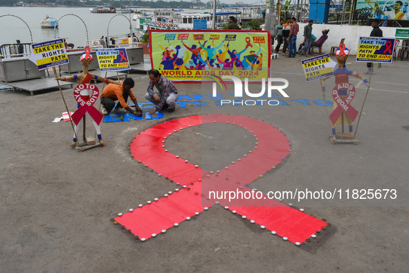 An activist from the Thalassemia and AIDS Prevention Society lights candles around a giant AIDS sign during a demonstration organized in Kol...