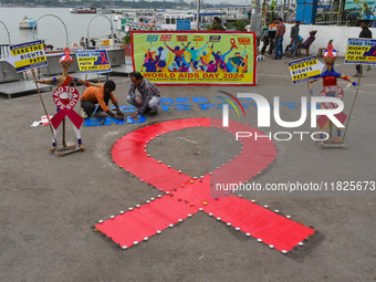 An activist from the Thalassemia and AIDS Prevention Society lights candles around a giant AIDS sign during a demonstration organized in Kol...