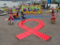 An activist from the Thalassemia and AIDS Prevention Society lights candles around a giant AIDS sign during a demonstration organized in Kol...