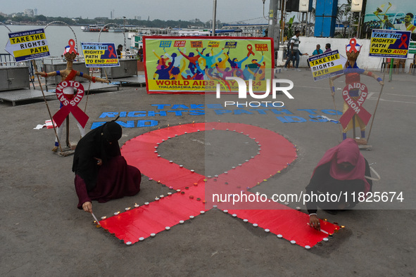 An activist from the Thalassemia and AIDS Prevention Society lights candles around a giant AIDS sign during a demonstration organized in Kol...