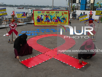 An activist from the Thalassemia and AIDS Prevention Society lights candles around a giant AIDS sign during a demonstration organized in Kol...