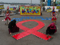 An activist from the Thalassemia and AIDS Prevention Society lights candles around a giant AIDS sign during a demonstration organized in Kol...