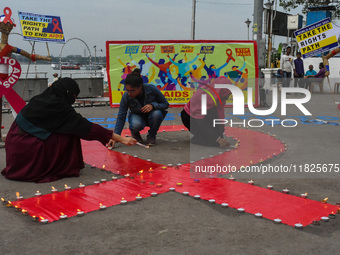 An activist from the Thalassemia and AIDS Prevention Society lights candles around a giant AIDS sign during a demonstration organized in Kol...