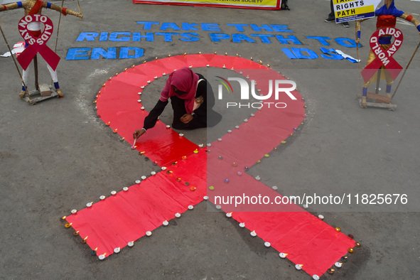 An activist from the Thalassemia and AIDS Prevention Society lights candles around a giant AIDS sign during a demonstration organized in Kol...