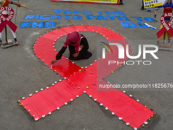 An activist from the Thalassemia and AIDS Prevention Society lights candles around a giant AIDS sign during a demonstration organized in Kol...