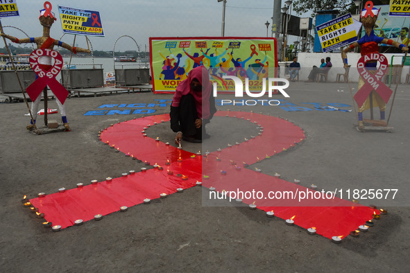 An activist from the Thalassemia and AIDS Prevention Society lights candles around a giant AIDS sign during a demonstration organized in Kol...