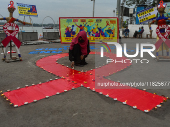 An activist from the Thalassemia and AIDS Prevention Society lights candles around a giant AIDS sign during a demonstration organized in Kol...