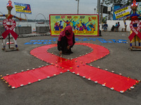 An activist from the Thalassemia and AIDS Prevention Society lights candles around a giant AIDS sign during a demonstration organized in Kol...