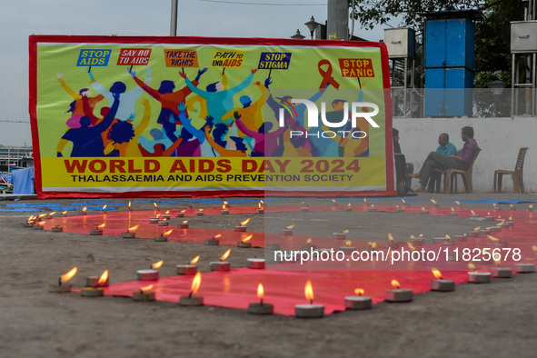 An activist from the Thalassemia and AIDS Prevention Society lights candles around a giant AIDS sign during a demonstration organized in Kol...