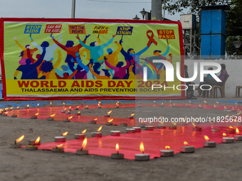 An activist from the Thalassemia and AIDS Prevention Society lights candles around a giant AIDS sign during a demonstration organized in Kol...