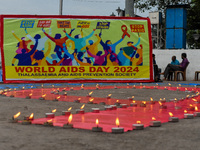 An activist from the Thalassemia and AIDS Prevention Society lights candles around a giant AIDS sign during a demonstration organized in Kol...