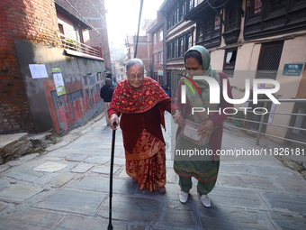 An elderly voter walks towards a nearby polling center to exercise her franchise in the local level by-election held in Kathmandu, Nepal, on...