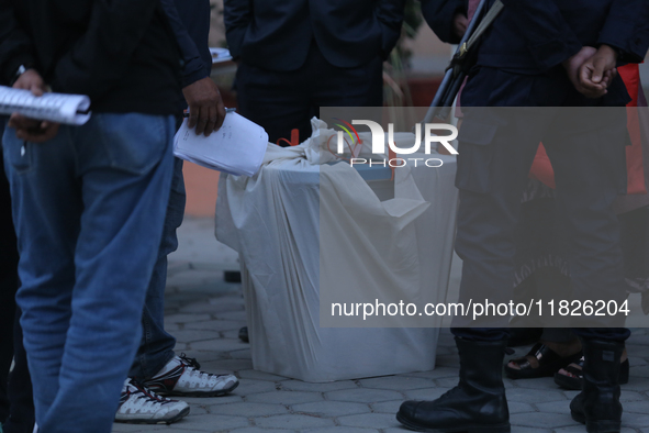 A sealed ballot box is guarded by election officials and security personnel at a local polling station after the completion of voting in loc...