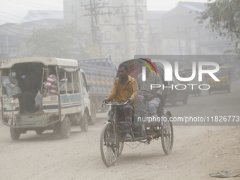 Commuters make their way amid unhealthy air quality in Dhaka, Bangladesh, on December 1, 2024. (