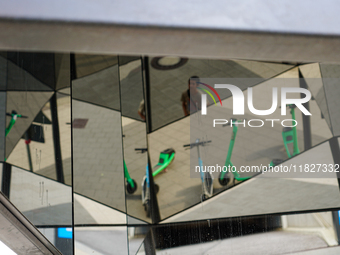 Geometric reflections of parked rental e-scooters appear in a pedestrian zone in Hamburg, Germany, on August 26, 2022. The photo shows the r...