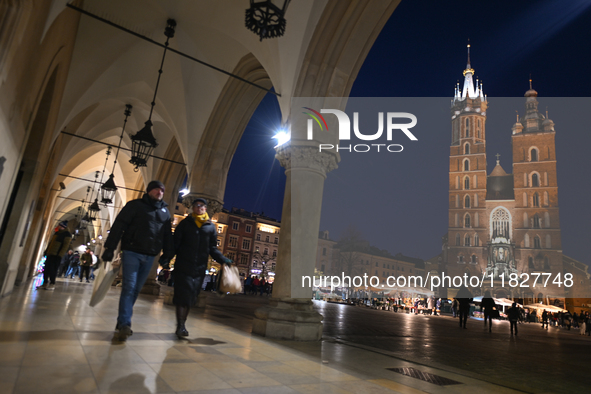 KRAKOW, POLAND - DECEMBER 01:   
A couple of visitors walks in a quiet corner of Krakow's UNESCO-listed Market Square contrasts with the bus...