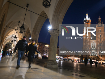 KRAKOW, POLAND - DECEMBER 01:   
A couple of visitors walks in a quiet corner of Krakow's UNESCO-listed Market Square contrasts with the bus...