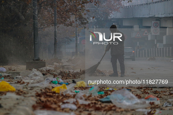 A worker sweeps along the roadside in Srinagar, Jammu and Kashmir, on December 02, 2024. Weather experts warn of heavy snowfall and a harsh...