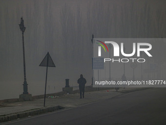 People jog on the banks of Dal Lake amid fog in Srinagar, Jammu and Kashmir, on December 02, 2024. Weather experts warn of heavy snowfall an...