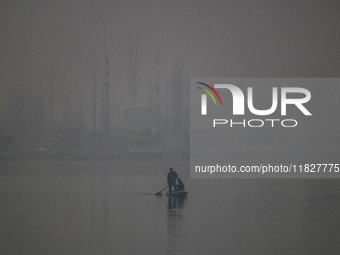 A man rows a boat in the waters of Dal Lake amid fog in Srinagar, Jammu and Kashmir, on December 02, 2024. Weather experts warn of heavy sno...