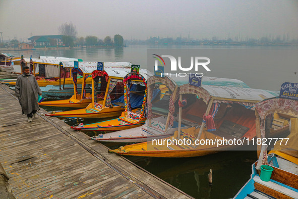 A man walks on the banks of Dal Lake amid fog in Srinagar, Jammu and Kashmir, on December 02, 2024. Weather experts warn of heavy snowfall a...