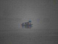 A man rows a boat in the waters of Dal Lake amid fog in Srinagar, Jammu and Kashmir, on December 02, 2024. Weather experts warn of heavy sno...