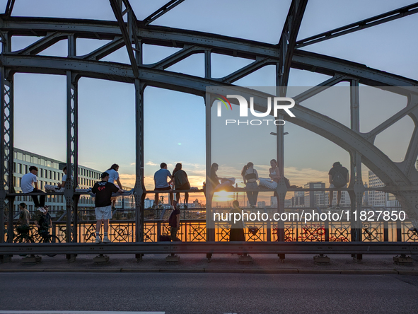 Young people gather on the Hackerbrucke in Munich, Bavaria, to view the sunset. This iconic bridge, which connects the central bus station (...