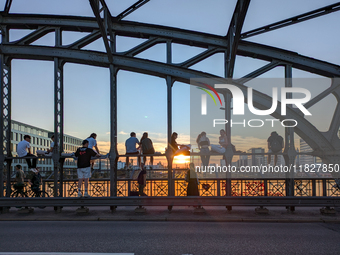 Young people gather on the Hackerbrucke in Munich, Bavaria, to view the sunset. This iconic bridge, which connects the central bus station (...