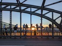 Young people gather on the Hackerbrucke in Munich, Bavaria, to view the sunset. This iconic bridge, which connects the central bus station (...