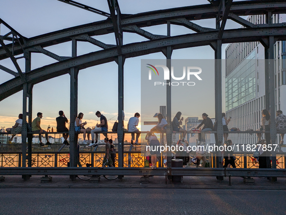 Young people gather on the Hackerbrucke in Munich, Bavaria, to view the sunset. This iconic bridge, which connects the central bus station (...