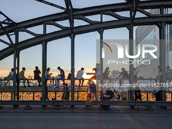 Young people gather on the Hackerbrucke in Munich, Bavaria, to view the sunset. This iconic bridge, which connects the central bus station (...