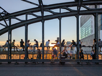 Young people gather on the Hackerbrucke in Munich, Bavaria, to view the sunset. This iconic bridge, which connects the central bus station (...