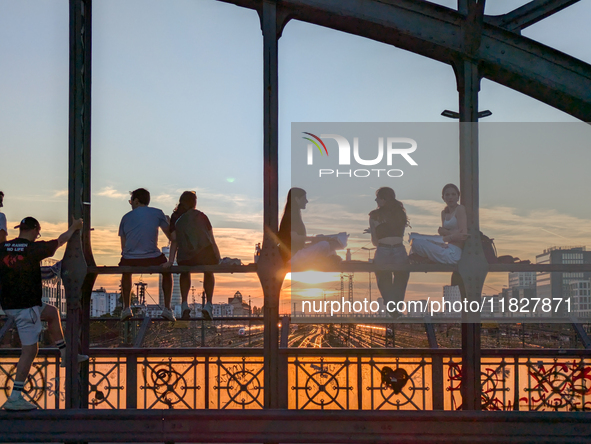 Young people gather on the Hackerbrucke in Munich, Bavaria, to view the sunset. This iconic bridge, which connects the central bus station (...