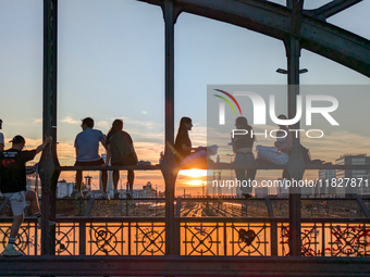 Young people gather on the Hackerbrucke in Munich, Bavaria, to view the sunset. This iconic bridge, which connects the central bus station (...