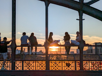 Young people gather on the Hackerbrucke in Munich, Bavaria, to view the sunset. This iconic bridge, which connects the central bus station (...