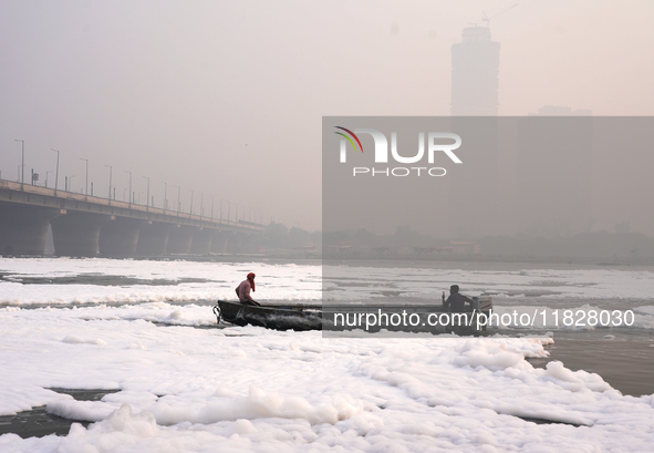 Workers for the Delhi water board move in a boat on the Yamuna River, which is covered in toxic foam, in New Delhi, India, on November 7, 20...