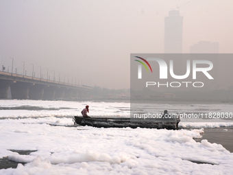 Workers for the Delhi water board move in a boat on the Yamuna River, which is covered in toxic foam, in New Delhi, India, on November 7, 20...