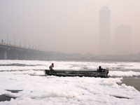 Workers for the Delhi water board move in a boat on the Yamuna River, which is covered in toxic foam, in New Delhi, India, on November 7, 20...